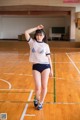 A woman in a white shirt and blue shorts on a basketball court.